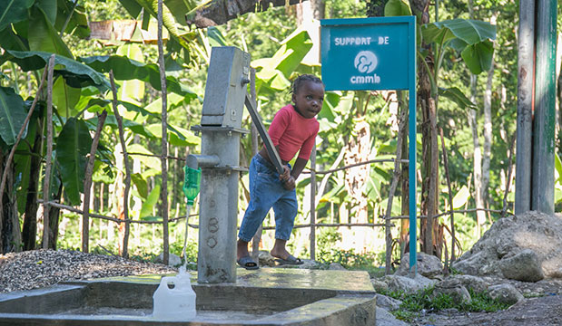 A child pumps water from a CMMB-supported well.