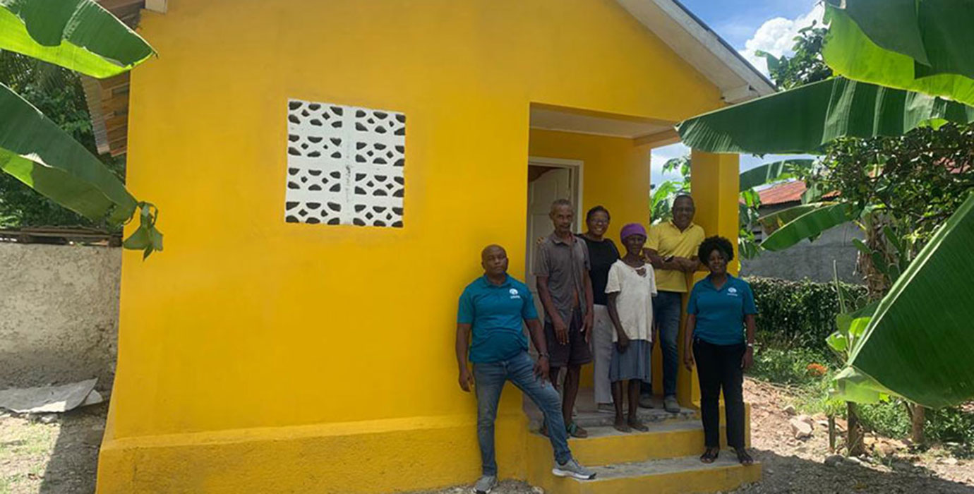A family stands in front of their new home.
