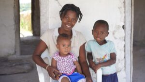 A woman sits with her children. They are smiling. 