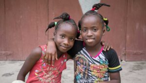 Two girls sit beside one another.